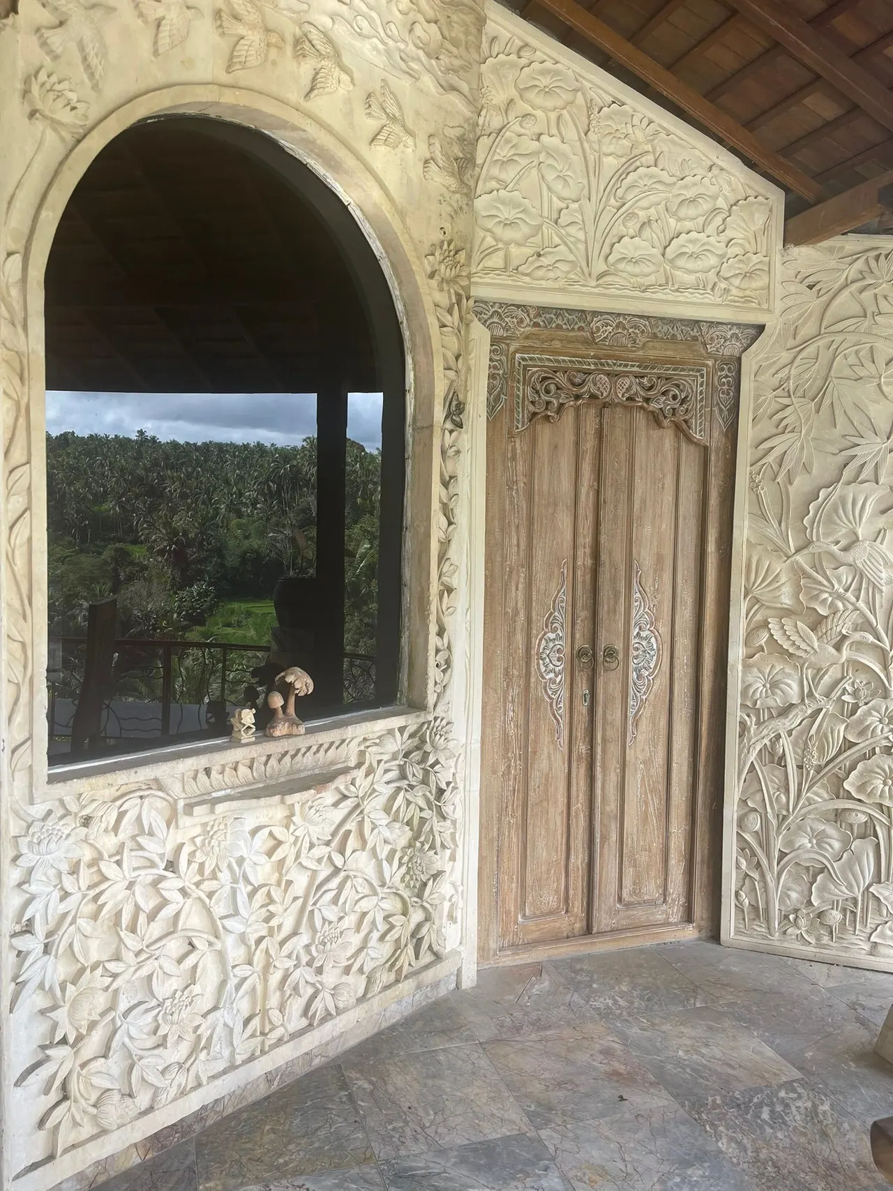 Carved stone walls around a wooden Balinese doorway