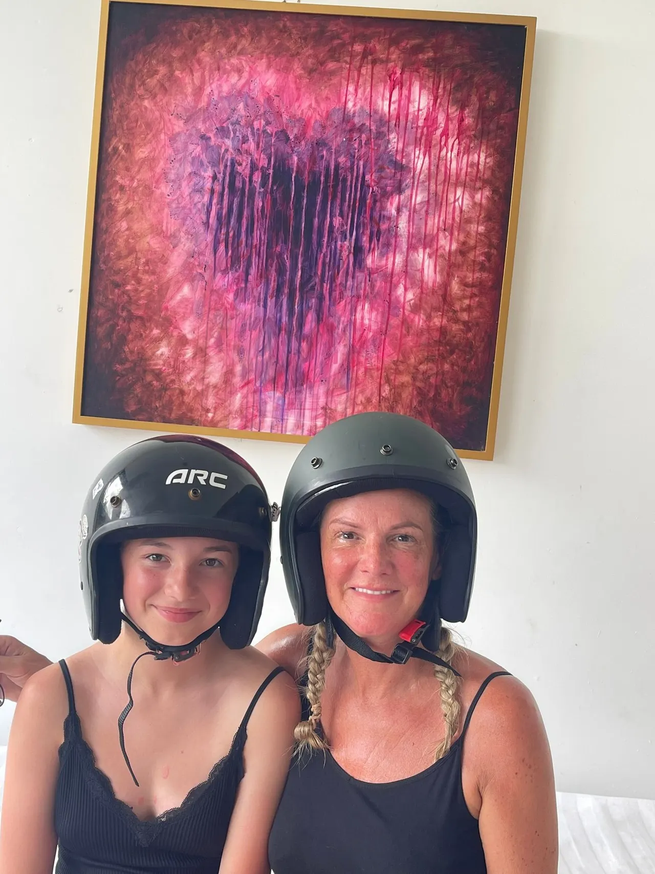 Guests in scooter helmets beneath a magenta painting