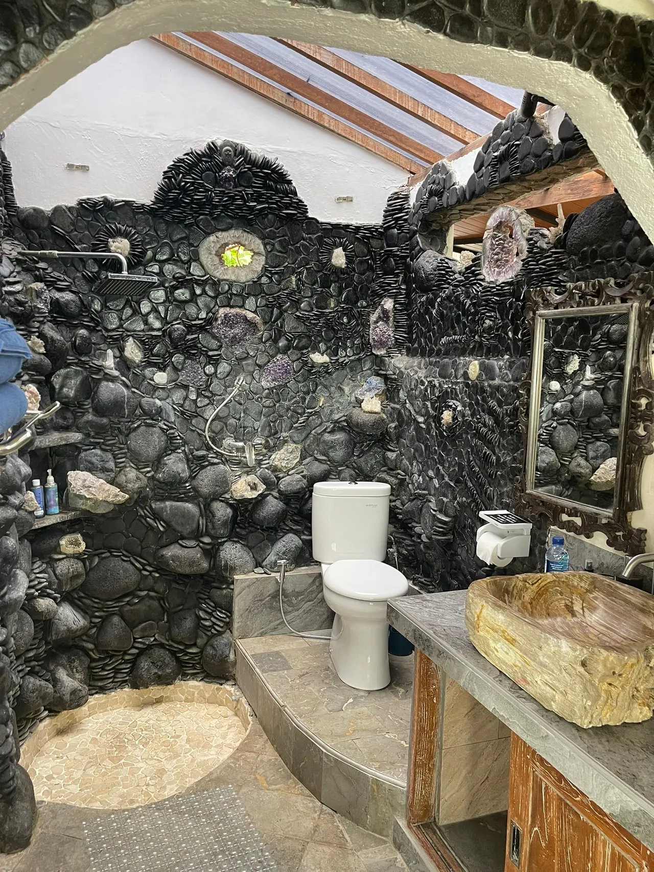 Bathroom walls of black river stone set with amethyst crystal