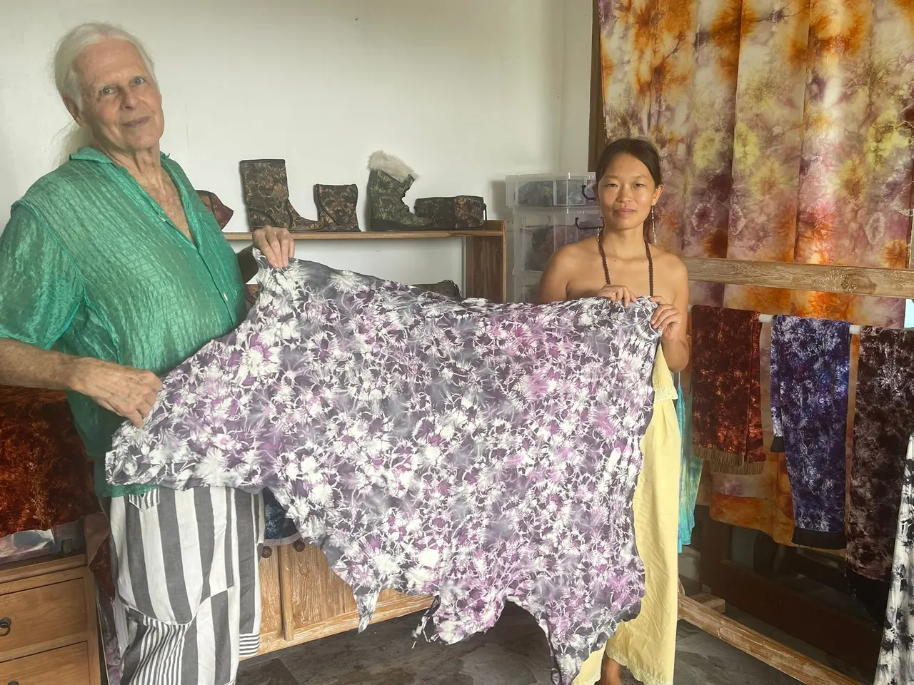 Two guests unfolding a finished dyed textile