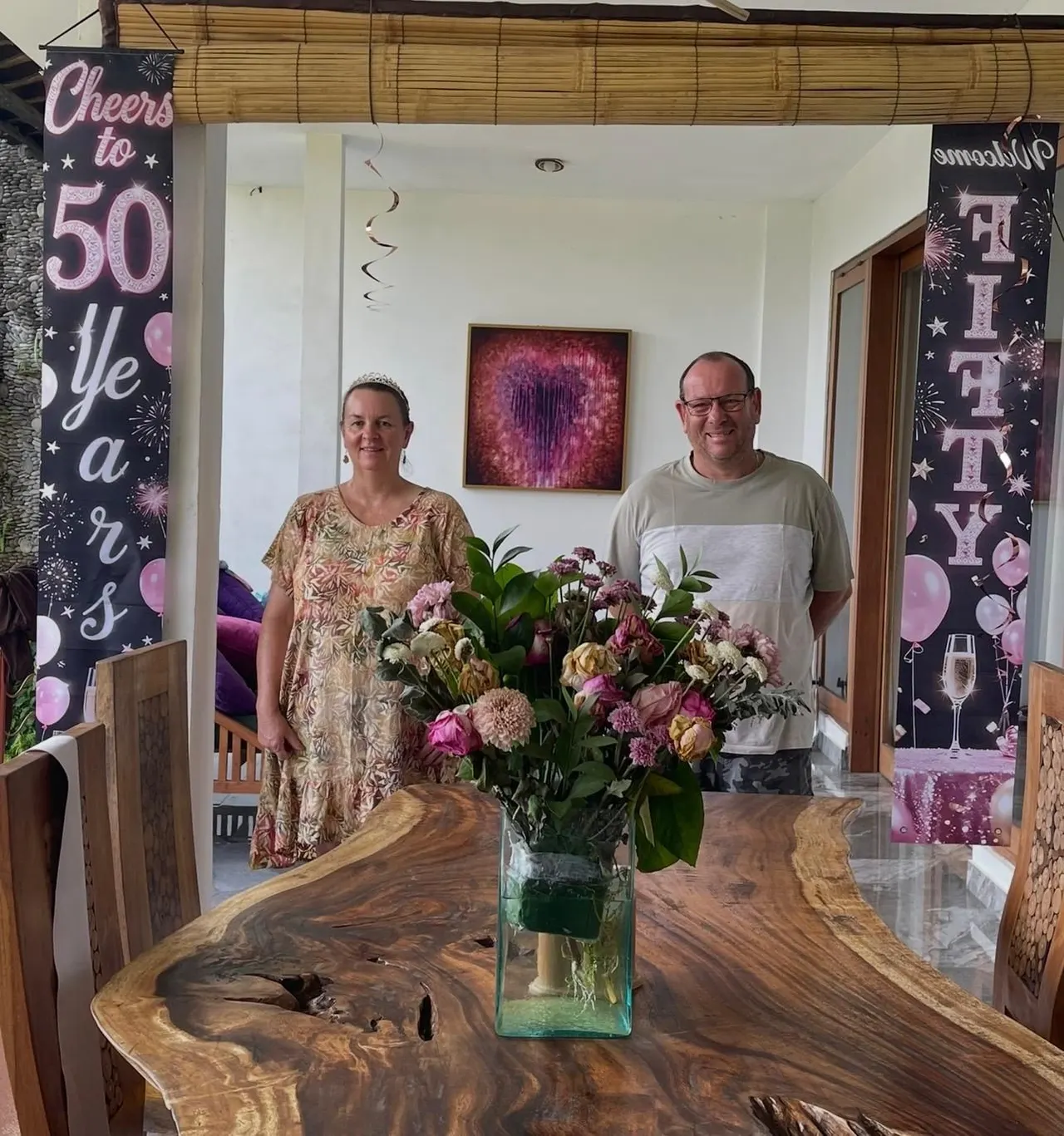 Guests beside a teak dining table decorated for a fiftieth birthday