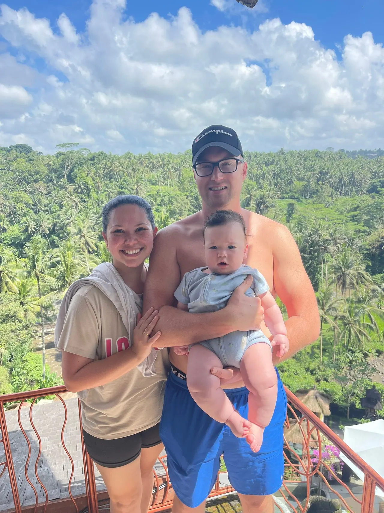 Young family holding their baby above the jungle valley